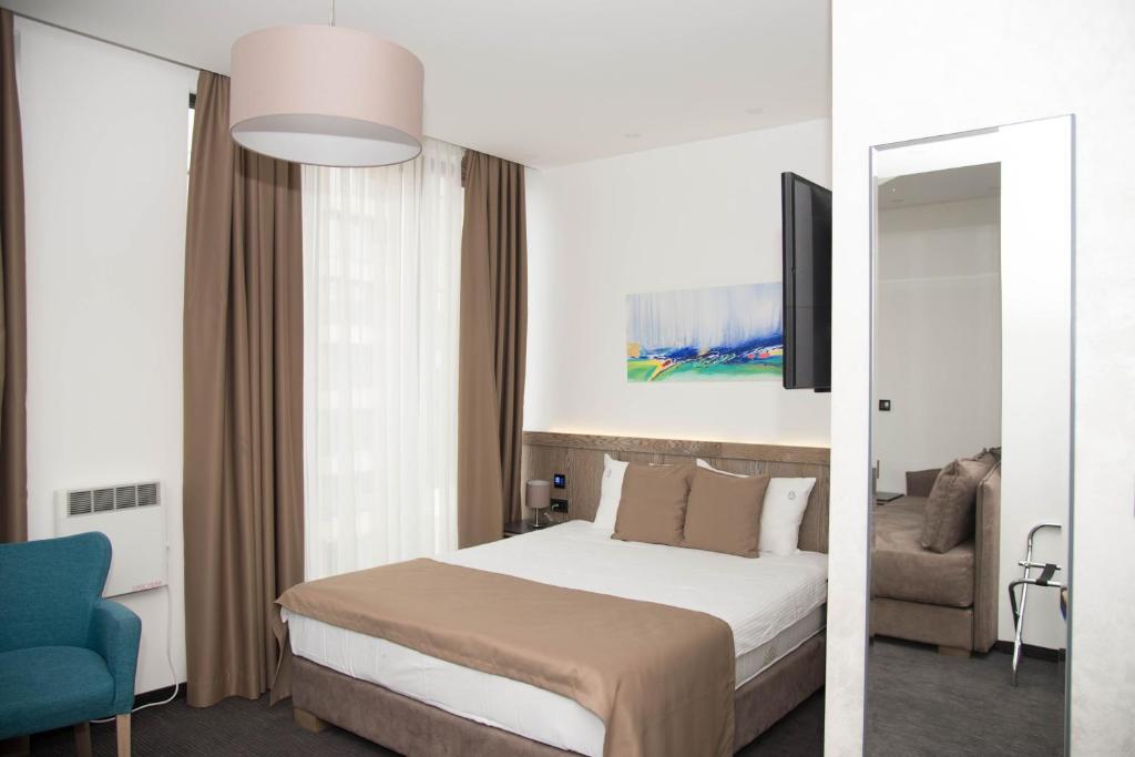 een hotelkamer met een bed en een blauwe stoel bij Apartman V&V in Zlatibor