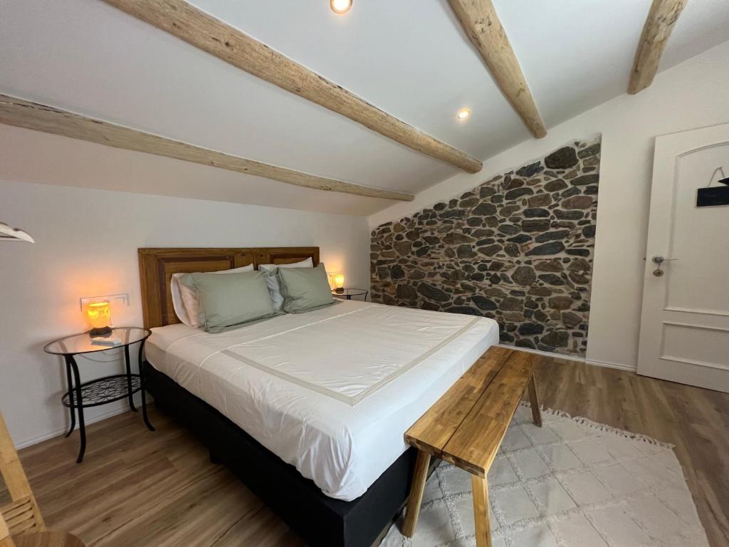 ein Schlafzimmer mit einem Bett und einer Steinmauer in der Unterkunft Can Jan Vives in Vidreres
