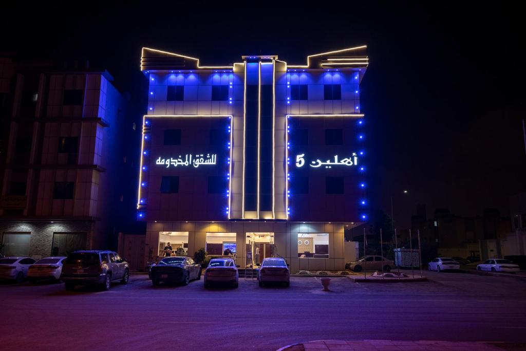 a lit up building with cars parked in a parking lot at Ahlin Suites 5 in Riyadh