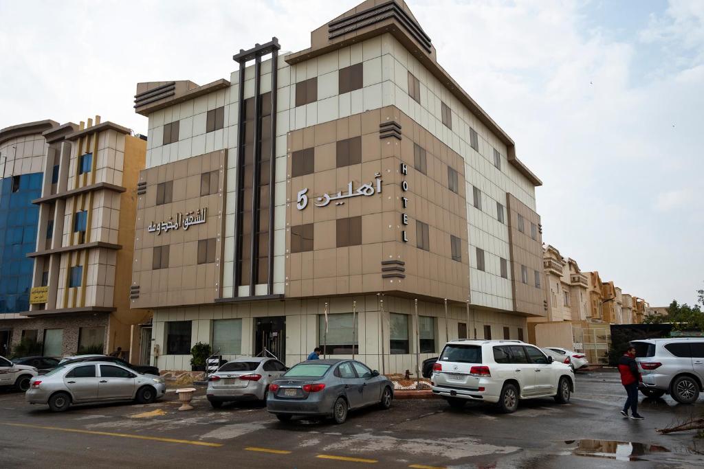 un gran edificio con coches estacionados en un estacionamiento en Ahlin Suites 5 en Riad