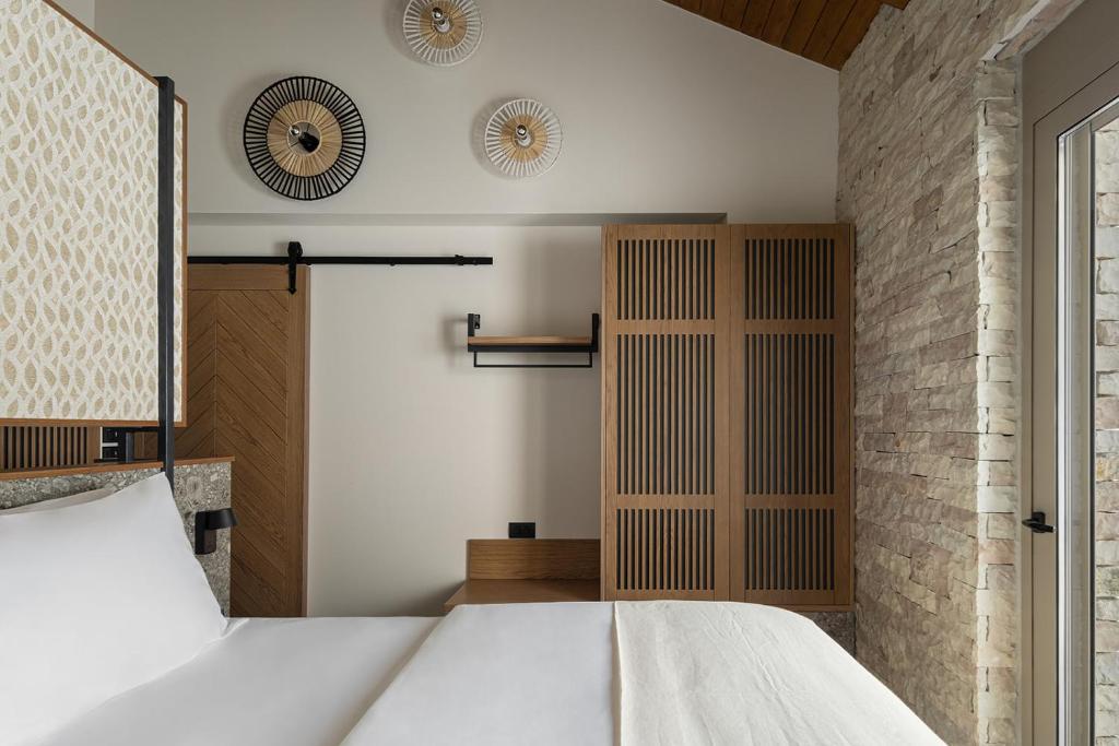 a bedroom with a white bed and a brick wall at Villa Vrachos luxury Living in Vrachos