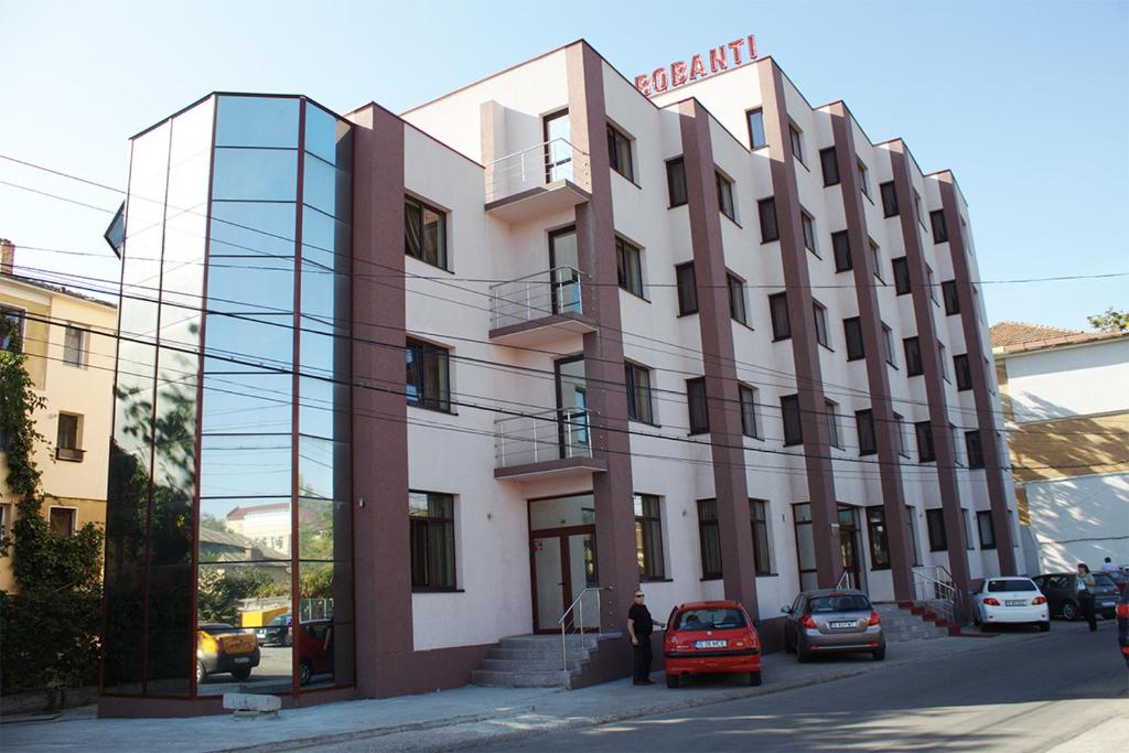een gebouw waar auto's voor geparkeerd staan bij Hotel Dorobanti in Iaşi