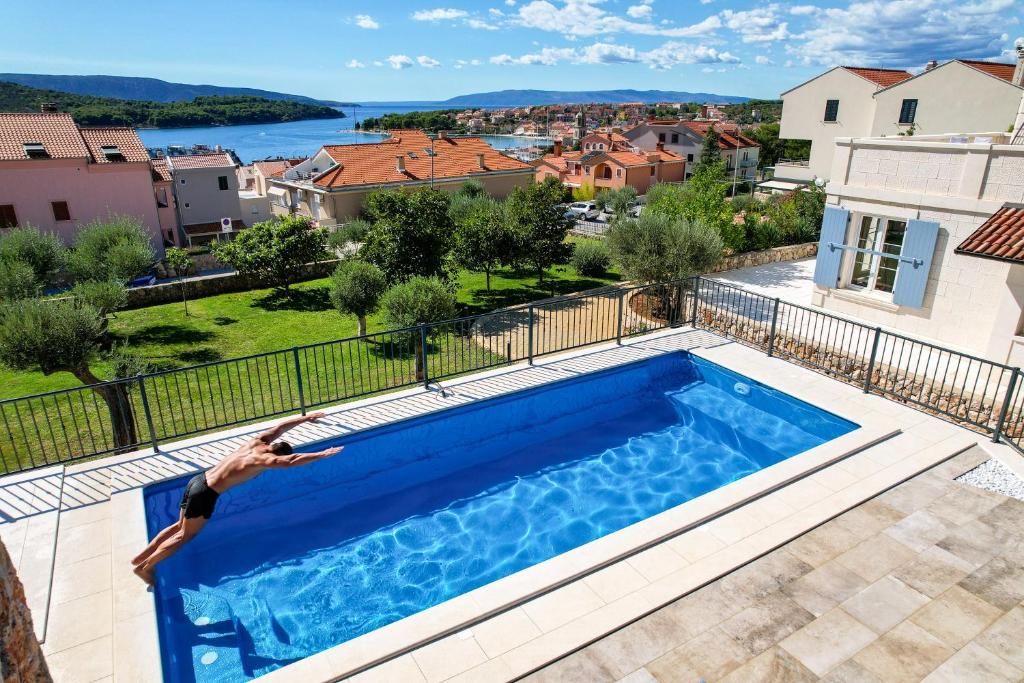 a man is laying on the edge of a swimming pool at Rooms Salvia in Cres