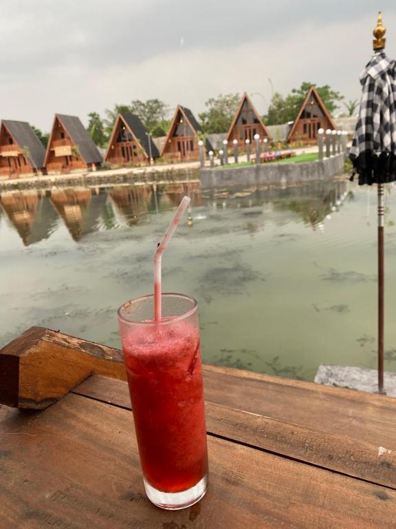 a drink sitting on a table next to a lake at Resort & Resto Talaga Sundayana in Subang