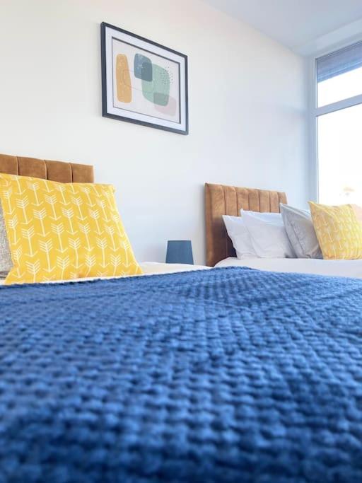 a bedroom with a blue bed with yellow pillows at Flitwick Luxury Apartment in Flitwick