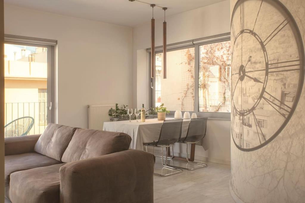 Luxury Apt with Parking-Living Stone Silver في أثينا: غرفة معيشة مع أريكة وطاولة مع ساعة