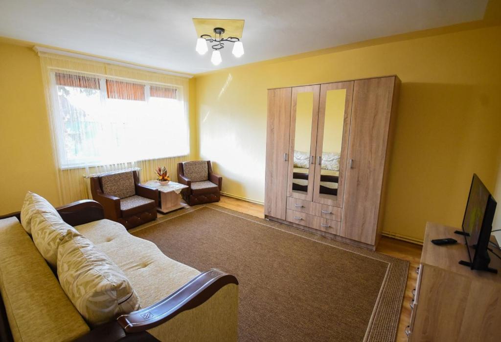 a living room with a couch and chairs and a television at Flower Apartment - Deluxe in Odorheiu Secuiesc