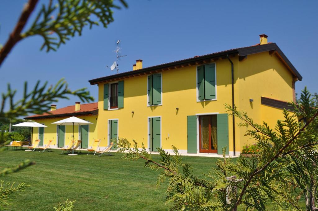a yellow house with green shutters and a yard at Agriturismo ai Ciliegi in Bardolino