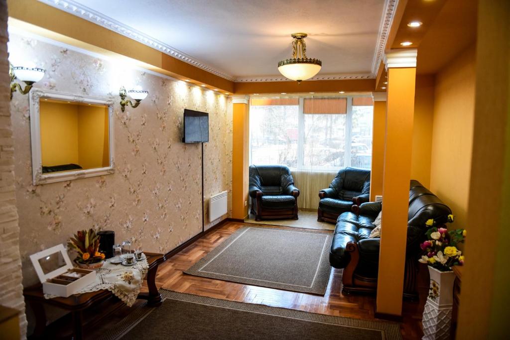 een woonkamer met lederen stoelen en een spiegel bij Flower Apartment - Standard in Odorheiu Secuiesc