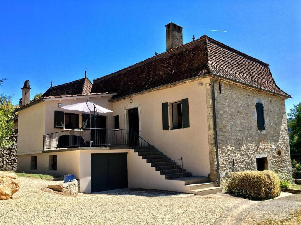 a large white house with a balcony and a garage at Gite le Roucayral , vue imprenable sur St Cirq Lapopie, deux chambres climatisées in Tour-de-Faure