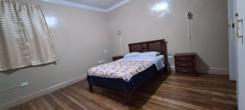 1 dormitorio con 1 cama y suelo de madera en Magic Hostal, en Quito