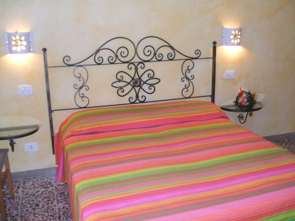 um quarto com uma cama com um cobertor listrado colorido em Su Ghindalu Guesthouse em Villanova Monteleone