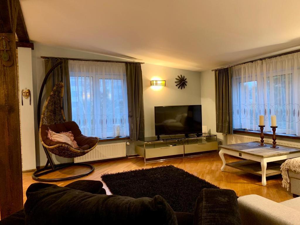 ein Wohnzimmer mit einem Sofa und einem Flachbild-TV in der Unterkunft Apartament z tarasem w Augustowie in Augustów