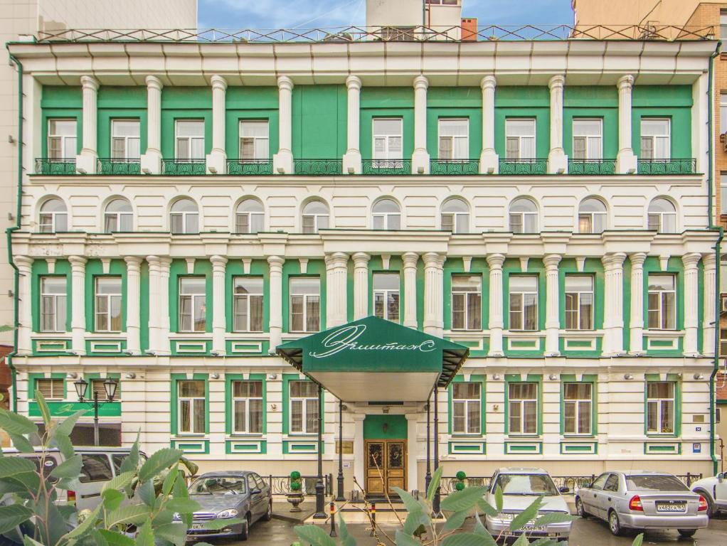 ein grünes und weißes Gebäude mit davor geparkt in der Unterkunft Hermitage Hotel Rostov-on-Don in Rostow am Don