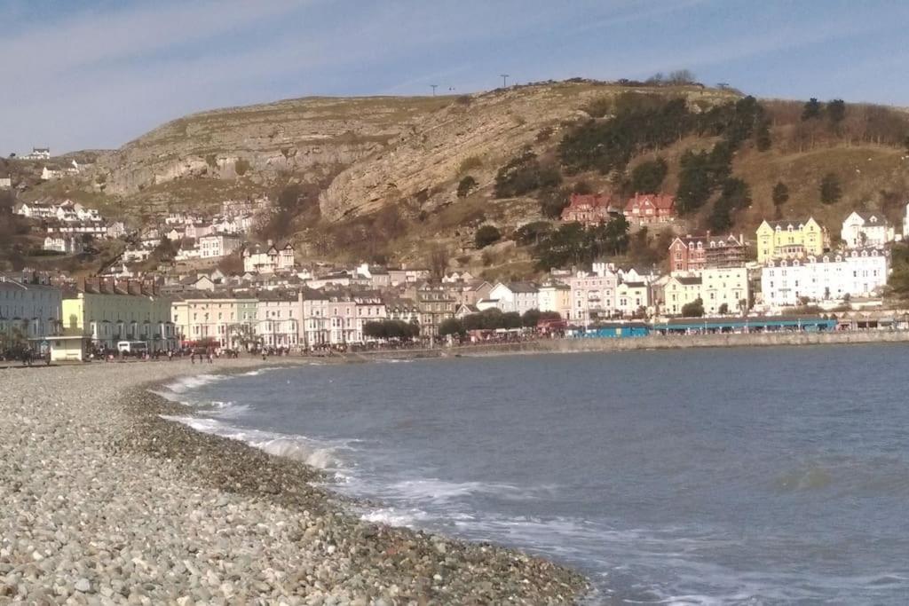 a view of a beach with houses on a hill at Spacious cosy apartment in Llandudno