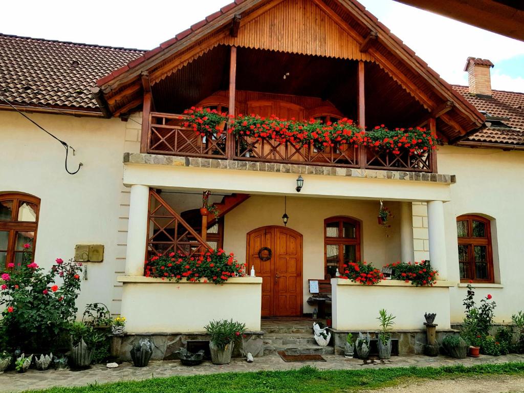 a house with a balcony with flowers on it at Enikő Vendégház in Cernatu de Sus