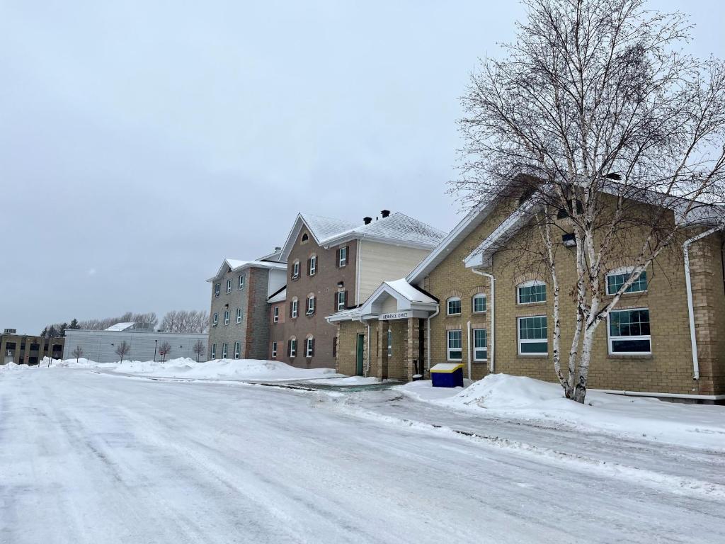 a snow covered street in front of a building at Residence & Conference Centre - Timmins in Timmins
