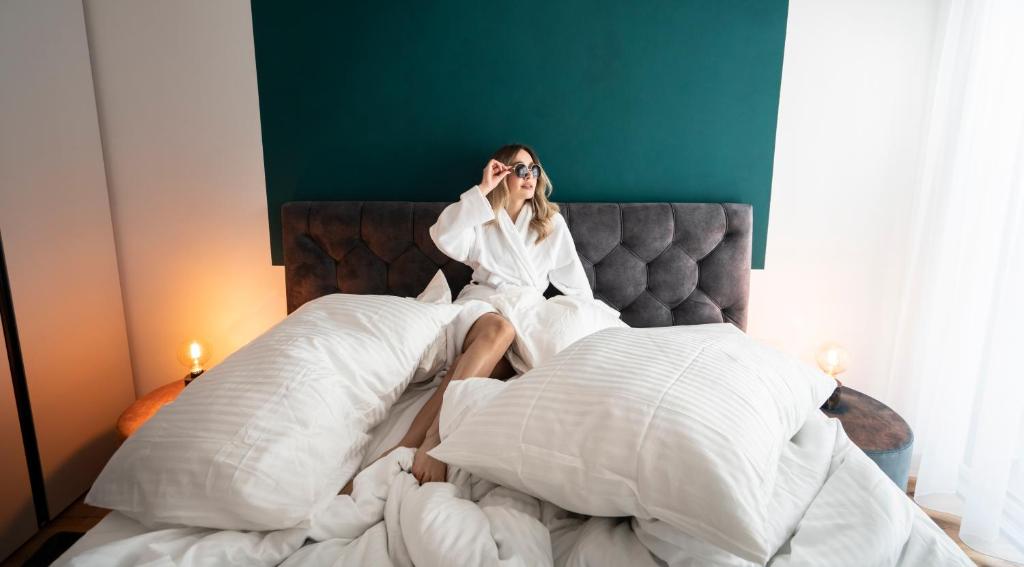 a woman sitting on a bed talking on a cell phone at T-Collection Premium Apartments in Vipiteno