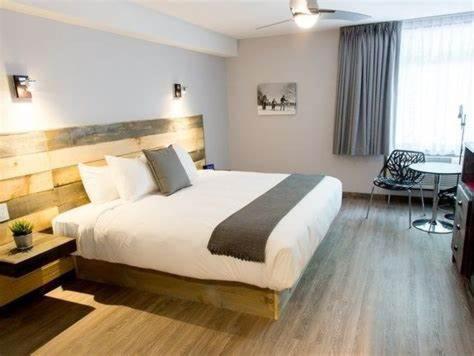 Un dormitorio con una cama grande y una mesa. en Hôtel Far Hills, en Val-Morin