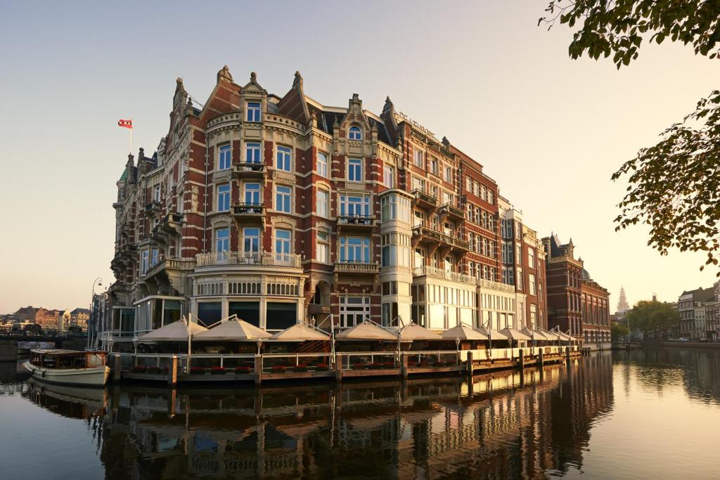 un gran edificio sentado en el agua junto a un canal en De L’Europe Amsterdam – The Leading Hotels of the World, en Ámsterdam