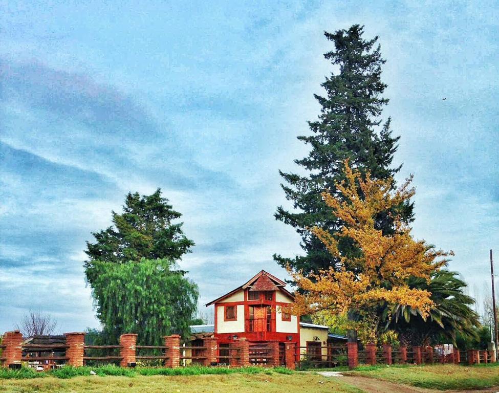 una casa en un campo con una valla y un árbol en Complejo Rincón del Sur San Rafael en San Rafael