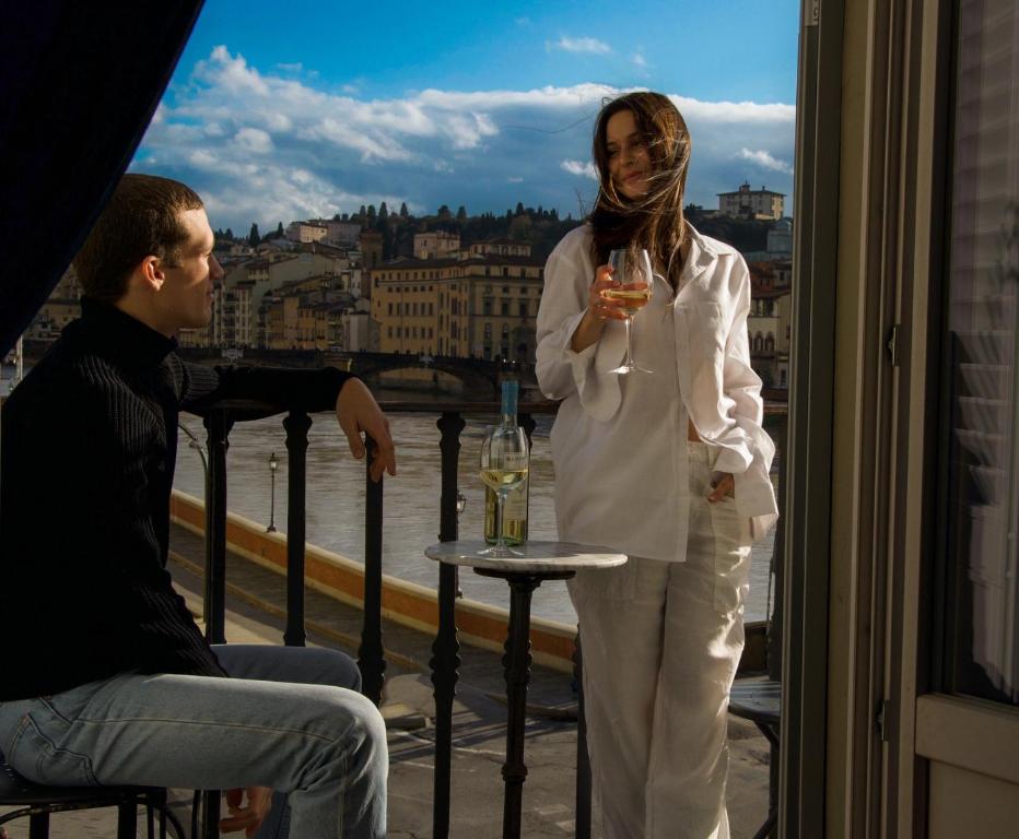 una mujer parada en un balcón sosteniendo una copa de vino en Residenza Vespucci, en Florencia