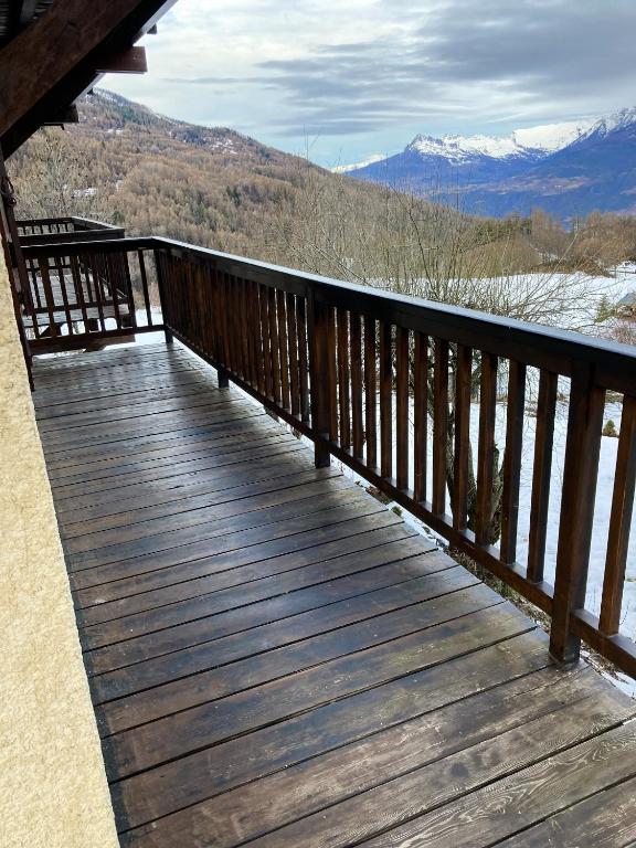 una terraza de madera con vistas a las montañas cubiertas de nieve en Appartement de 2 chambres avec balcon amenage a Les Orres a 2 km des pistes en Les Orres