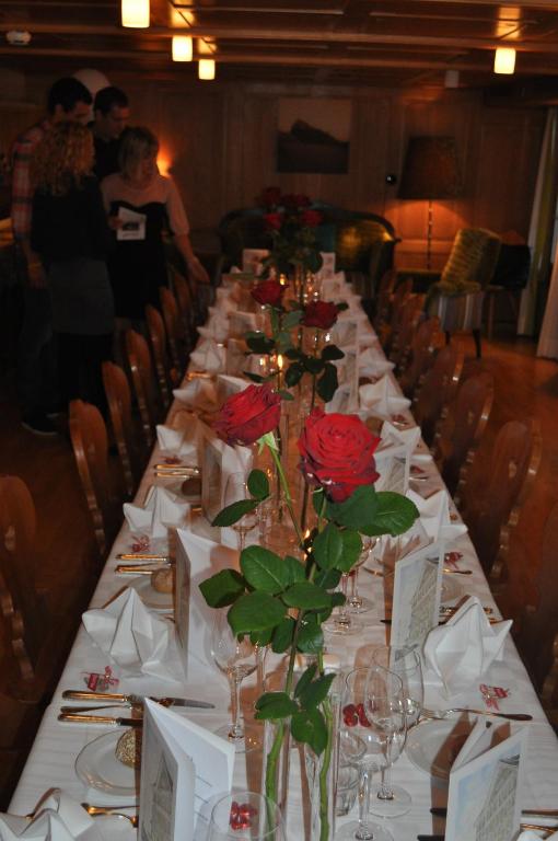 a long table with red roses in vases on it at Hotel Engelberg "mein Trail Hotel" in Engelberg
