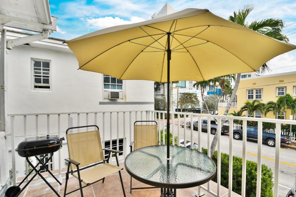 uma mesa e cadeiras com um guarda-sol amarelo numa varanda em Seaheights Villa em Miami Beach