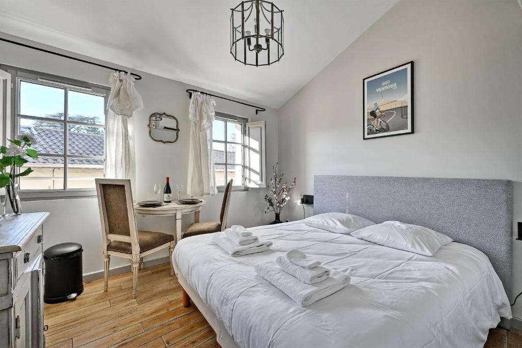 sypialnia z dużym białym łóżkiem i stołem w obiekcie Au cœur des Papes, dans bâtisse de charme studios & appartements en cœur de ville w Awinionie