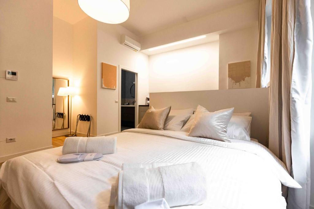 um quarto com uma cama grande com lençóis brancos e almofadas em Divini Gae Aulenti em Milão