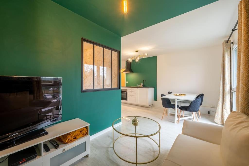 uma sala de estar com um sofá, uma televisão e uma mesa em Appartement Cosy Art Déco/ Proche centre-ville em Nantes