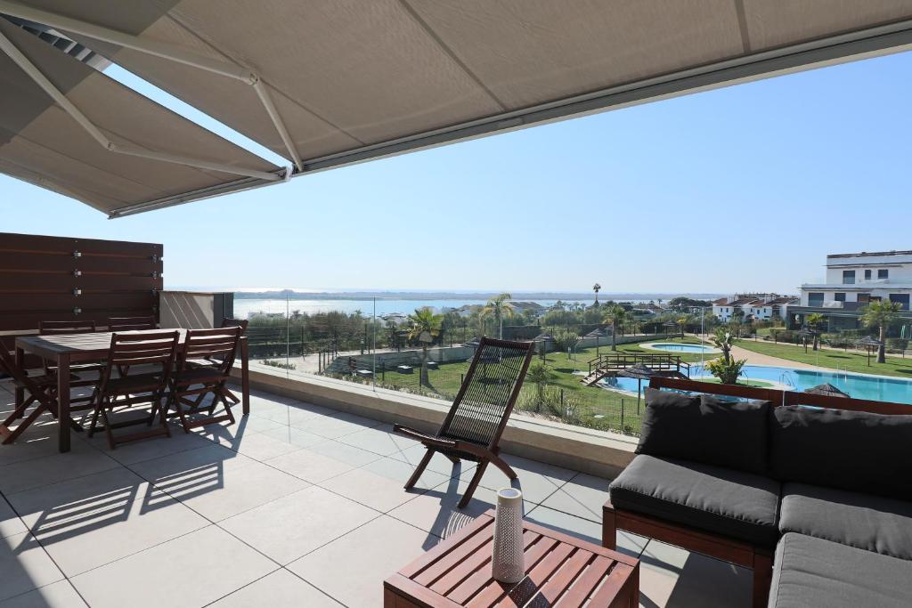 balkon z kanapą, stołem i krzesłami w obiekcie Enjoy La Reserva El Rompido w mieście El Rompido