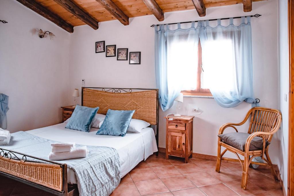 a bedroom with two beds and a chair and a window at Sa Ruscitta in SantʼAntìoco