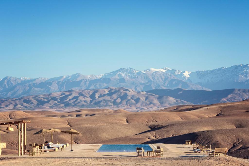 a pool in the desert with mountains in the background at Alkamar Camp Agafay in El Karia