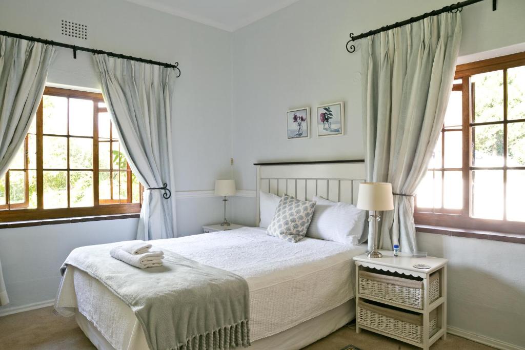 una camera da letto con un letto e due finestre di Grace Guest House a Johannesburg