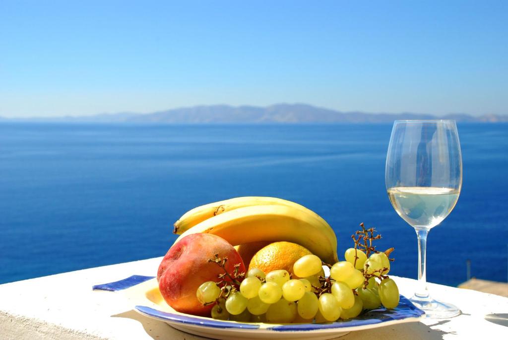 Istérnia的住宿－Aelia Mare Penthouse，桌上的水果盘和一杯葡萄酒
