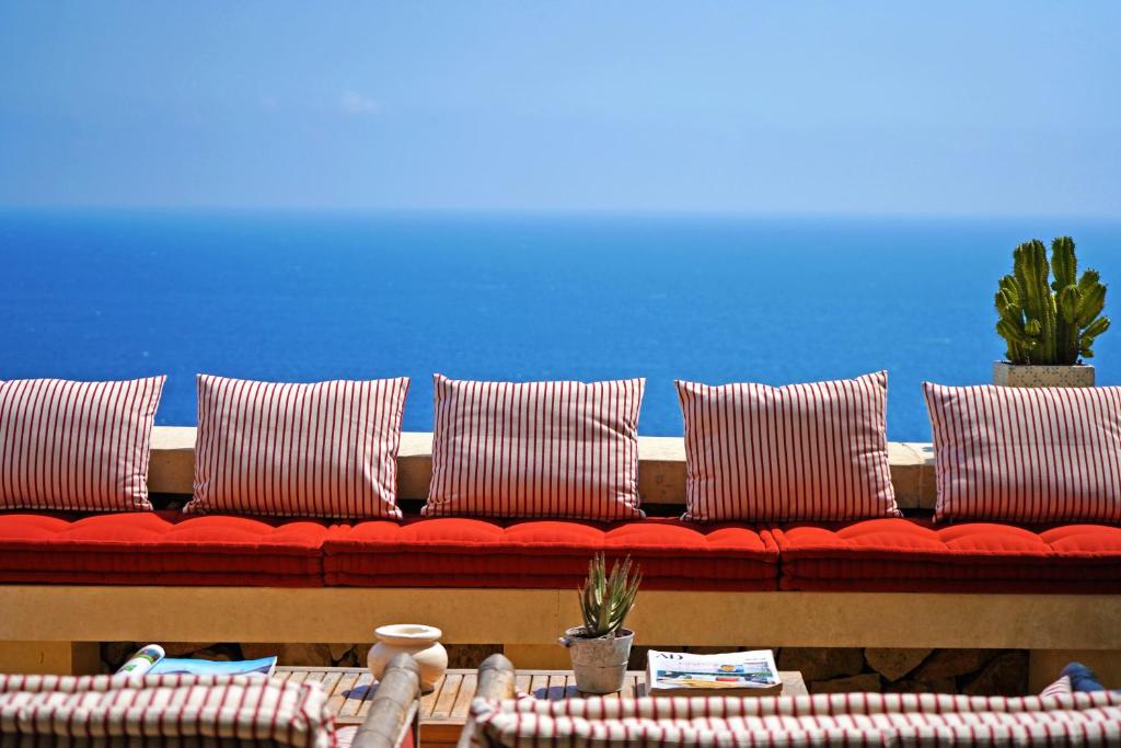 een rode bank met kussens en een blauwe muur bij Le Capase Resort Salento in Santa Cesarea Terme