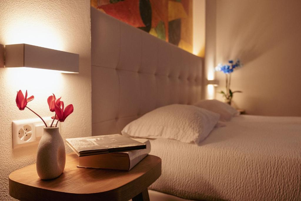 a bedroom with a bed and a table with a vase with flowers at Hotel Morgana in Mendrisio
