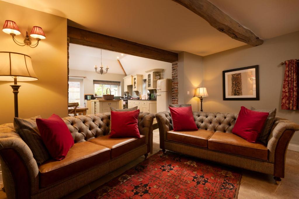 un soggiorno con 2 divani e cuscini rossi di The Dovecote a York