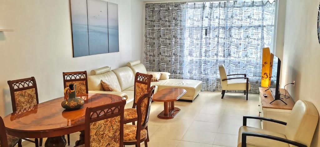 een woonkamer met een tafel en stoelen bij Large apartment with sea view in Bat Yam