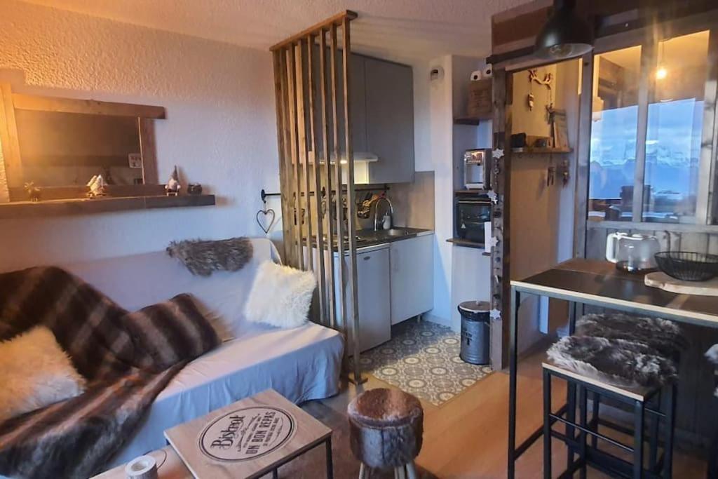 ein Wohnzimmer mit einem Sofa und einer Küche in der Unterkunft Studio montagnard vue splendide ALPE D HUEZ LES PASSEAUX in Huez
