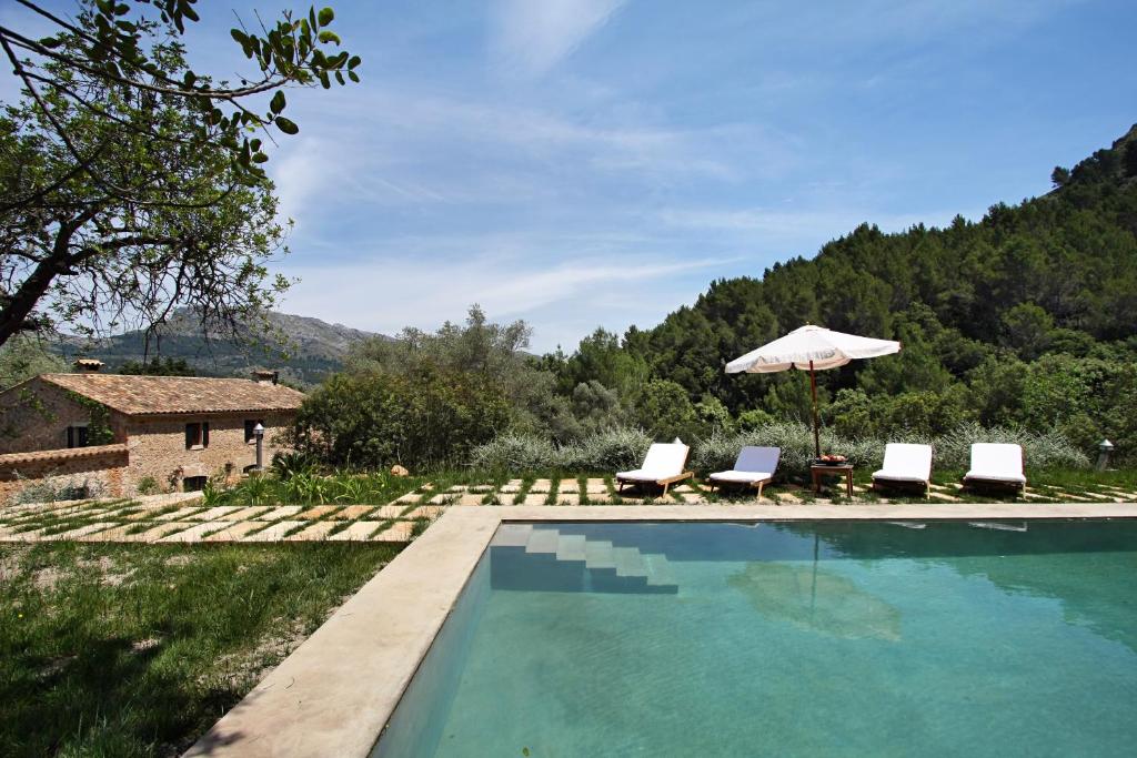 a swimming pool with two chairs and an umbrella at Villa Pascol in Pollença