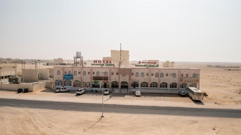 un grand bâtiment au milieu d'un désert dans l'établissement Arabian Sands Hotel فندق الرمال العربية, à Haymāʼ