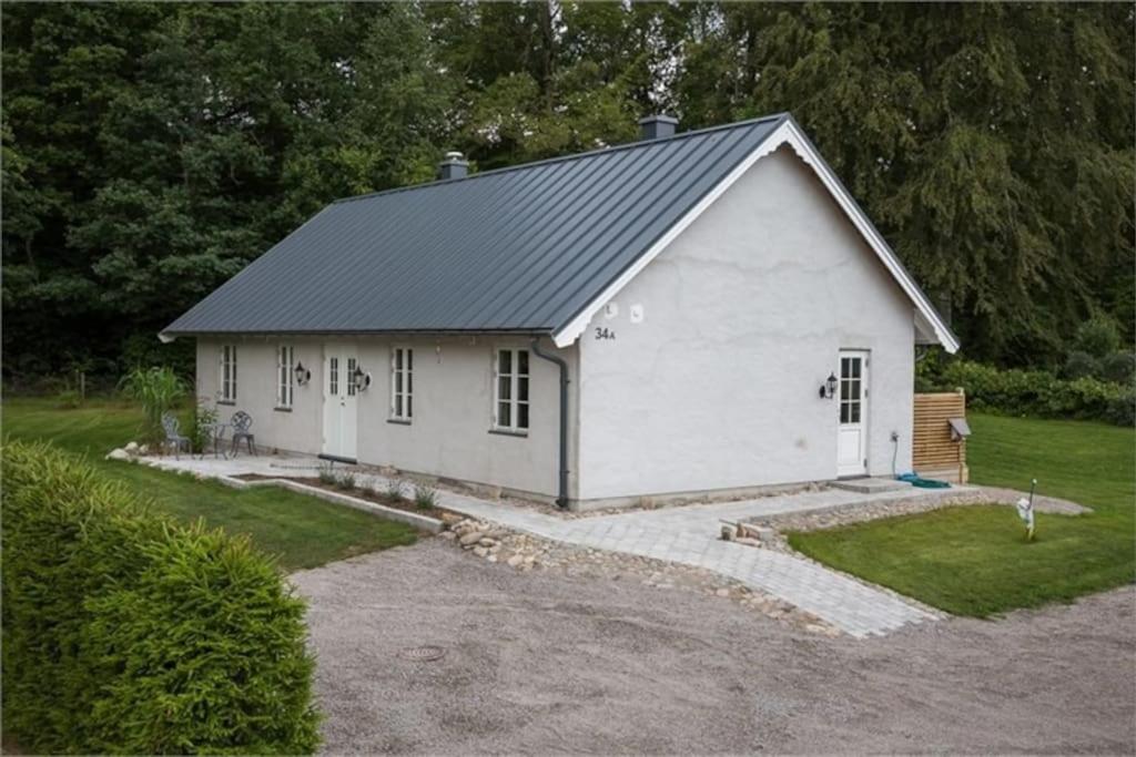 un granero blanco con techo de gambrel en Beautiful and cosy house near the lake en Olofström
