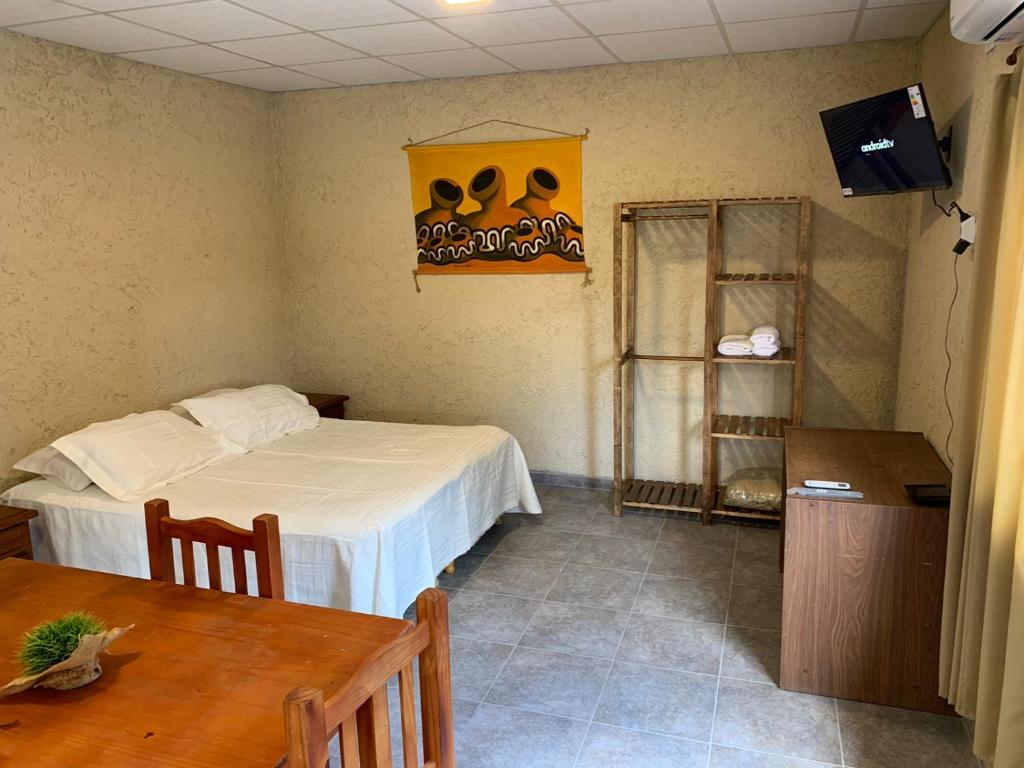 Habitación pequeña con cama, mesa y TV. en Departamento LOFT Centrico en San Rafael