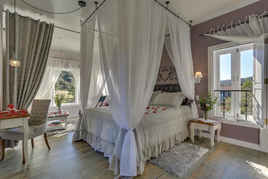 a bedroom with a canopy bed and a table and chairs at Pousada Cantos e Encantos in Urubici