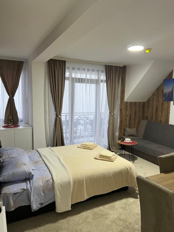 a bedroom with a large bed and a couch at GENCIAN RESORT in Kopaonik