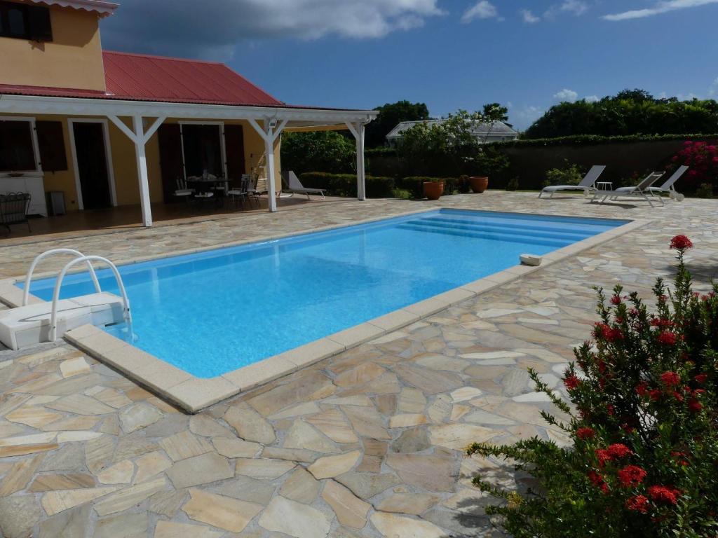 een zwembad met een stenen patio en een huis bij Villa Magnifique piscine & jardin in Baie-Mahault