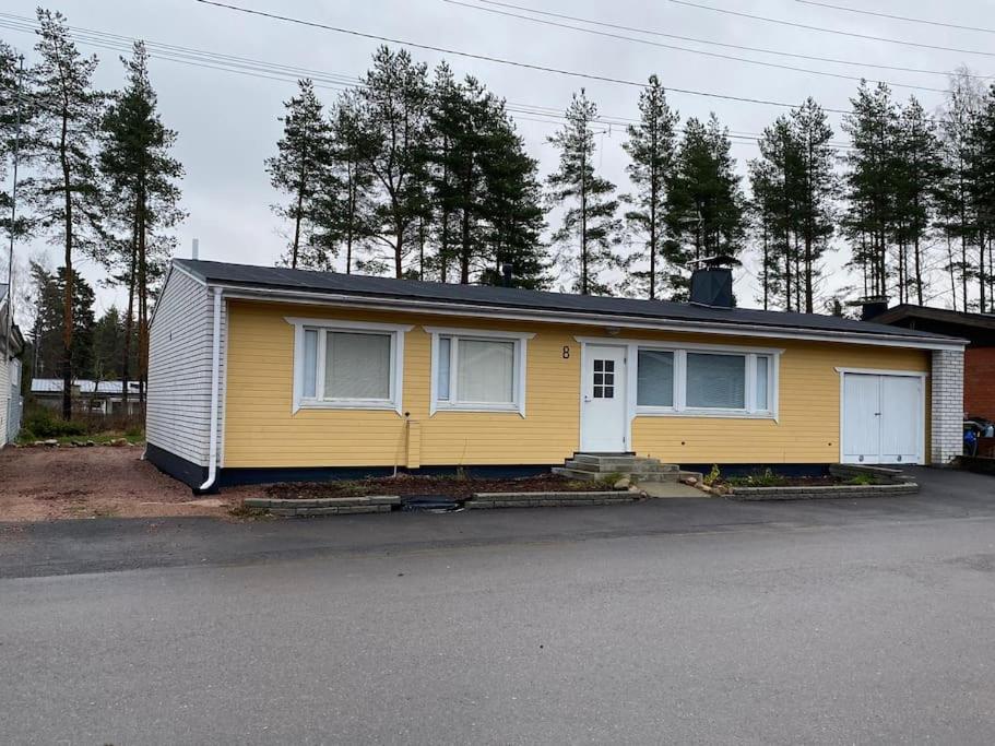 uma casa amarela sentada ao lado de uma rua em Saunallinen iso omakotitalo em Kotka